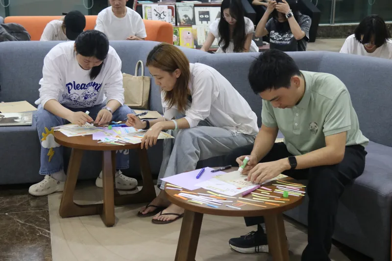 参与者在桌前专注书写、拼贴和粘贴自己的创作